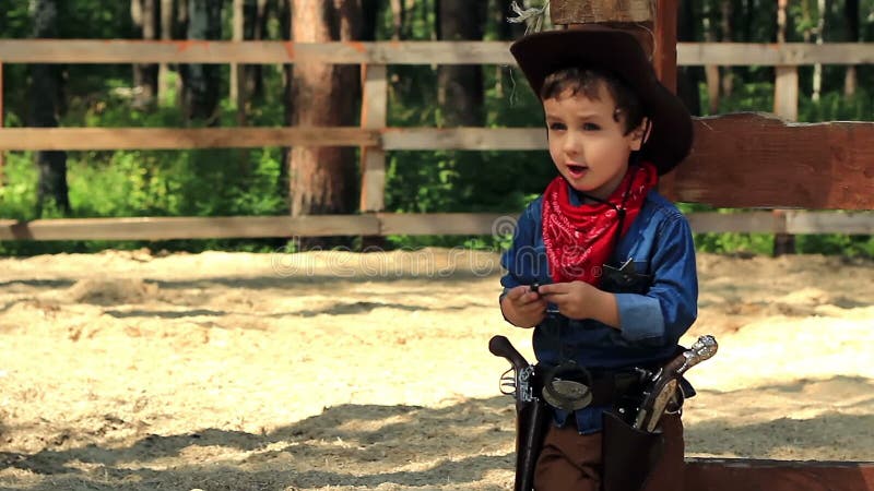 Petit cowboy se tenant près d'une barrière en bois banque de vidéos