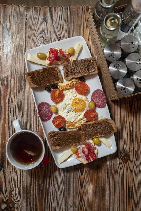 Petit déjeuner avec l'oeuf au plat, le pain de seigle, la grenade, la pâte de caroube, les fromages, les olives, le salami sec, l images libres de droits Petit déjeuner avec l'oeuf au plat, le pain de seigle, la grenade, la pâte de caroube, les fromages, les olives, le salami sec, l images libres de droits