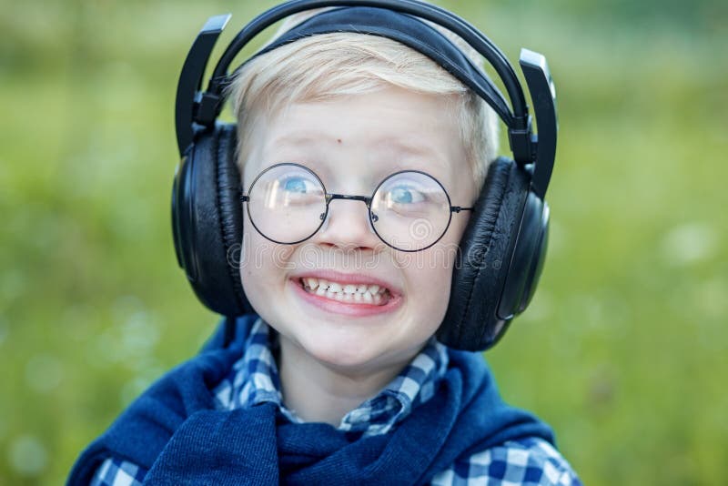 Petit enfant gai écoutant des chansons dans des écouteurs Le concept de la musique, de l'éducation et du mode de vie photo stock Petit enfant gai écoutant des chansons dans des écouteurs Le concept de la musique, de l'éducation et du mode de vie photo stock