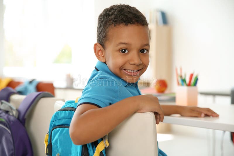 Petit enfant mignon s'asseyant au bureau dans la salle de classe photographie stock libre de droits Petit enfant mignon s'asseyant au bureau dans la salle de classe photographie stock libre de droits
