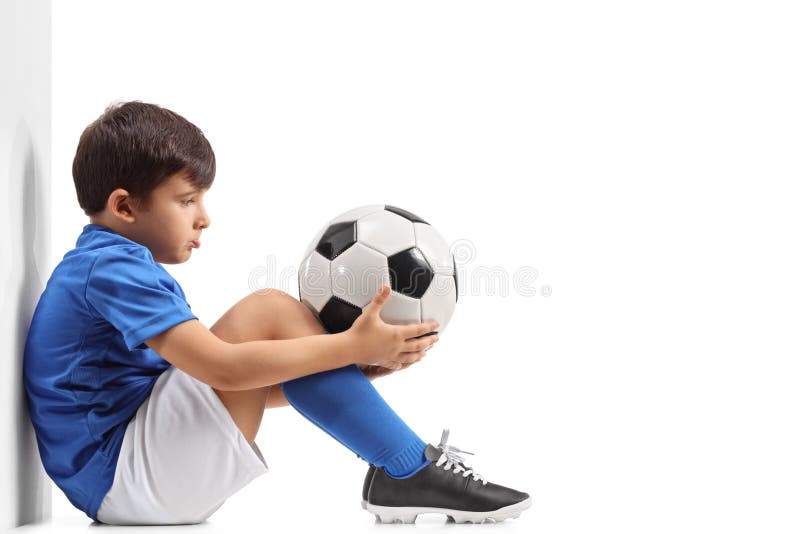 Petit footballer déçu se penchant contre un mur