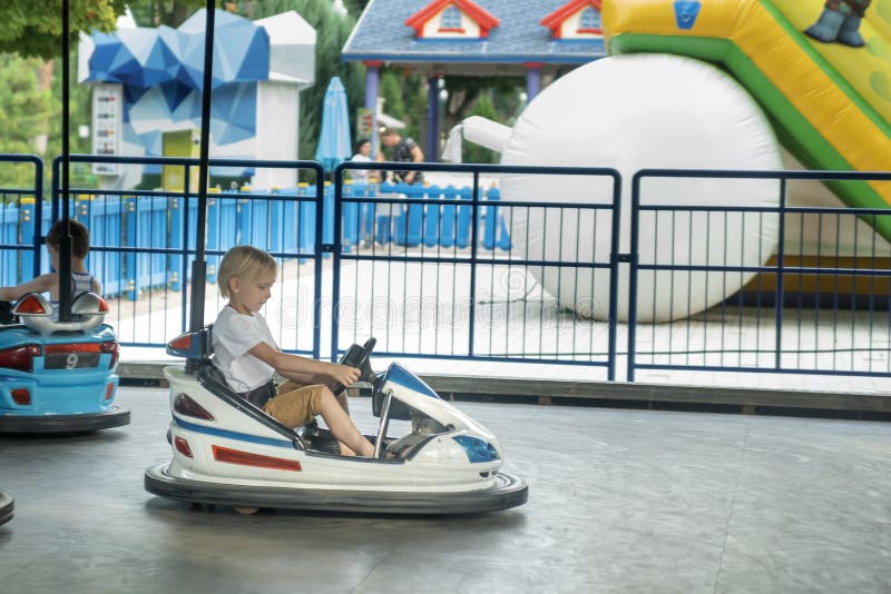 Les Enfants Conduisent Des Voitures électriques Dans Le Parc D'attractions  Enfance Heureuse Parc à Thème Conduite D'auto Tamponneuse