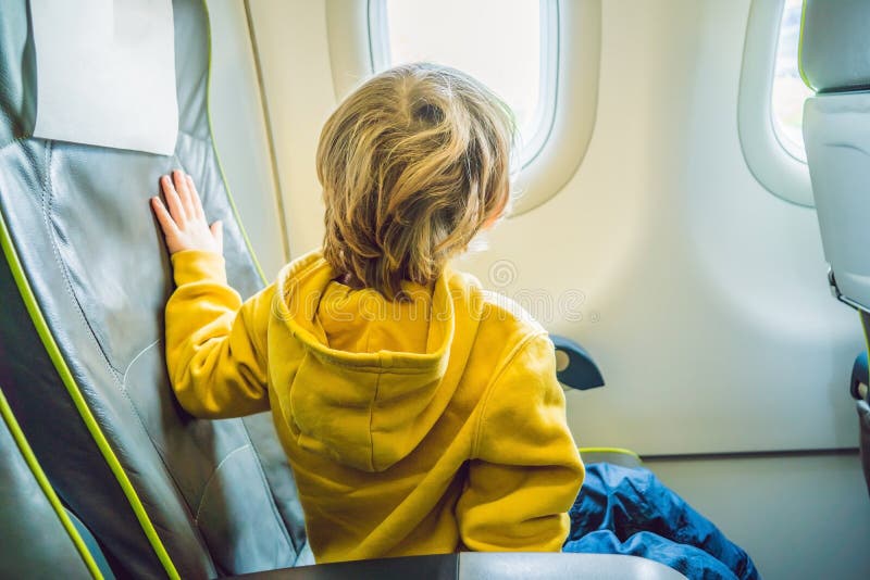 Petit garçon dans l'avion regardant la fenêtre photos libres de droits Petit garçon dans l'avion regardant la fenêtre photos libres de droits