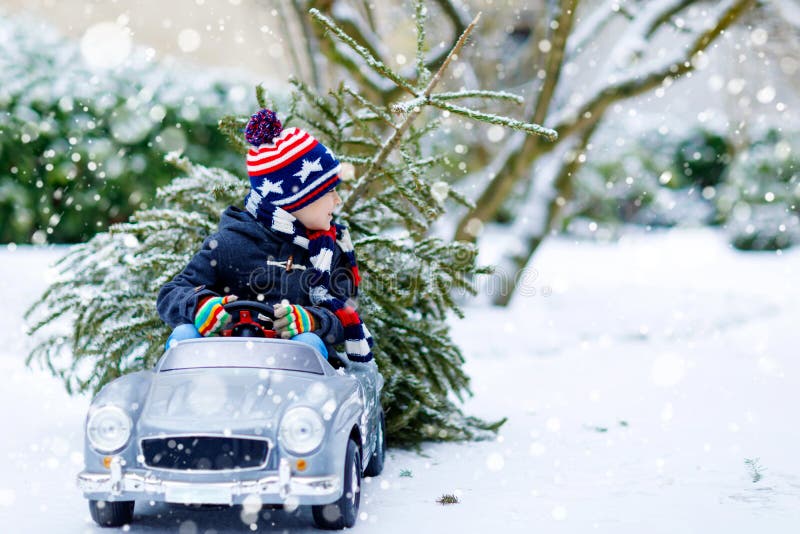 Petit garçon de sourire drôle d'enfant conduisant la voiture de jouet avec l'arbre de Noël photos libres de droits Petit garçon de sourire drôle d'enfant conduisant la voiture de jouet avec l'arbre de Noël photos libres de droits