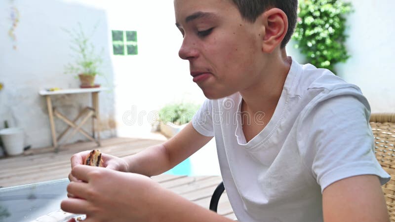 Petit garçon dégustant un snack à une table extérieure banque de vidéos