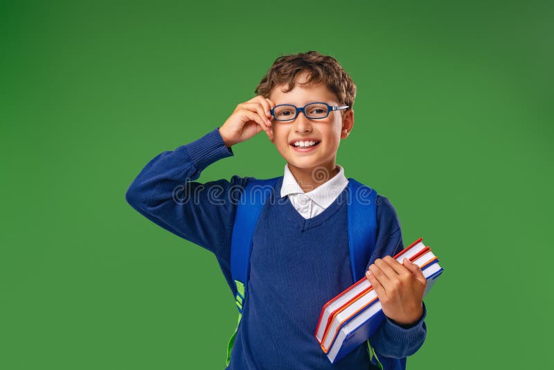 Petit garçon heureux avec des lunettes et l'uniforme avec un grand sac à dos s'amusant à l'école photo stock