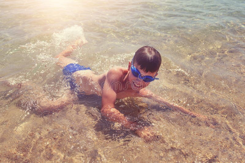 Petit garçon heureux jouant sur la plage dans l'eau image libre de droits Petit garçon heureux jouant sur la plage dans l'eau image libre de droits