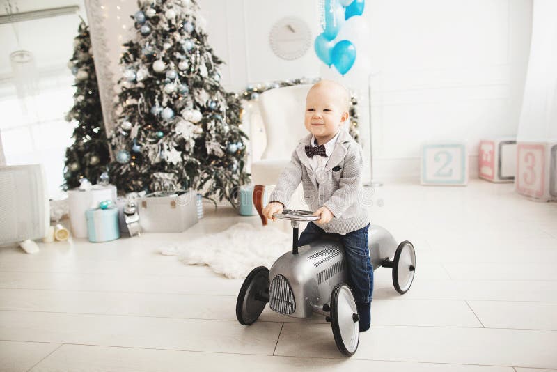 Petit garçon heureux montant une voiture de jouet, sur le fond de la salle décorée par Noël photos stock Petit garçon heureux montant une voiture de jouet, sur le fond de la salle décorée par Noël photos stock