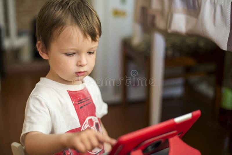 Petit garçon jouant avec le comprimé numérique enfant à l'aide d'un comprimé numérique photos libres de droits Petit garçon jouant avec le comprimé numérique enfant à l'aide d'un comprimé numérique photos libres de droits