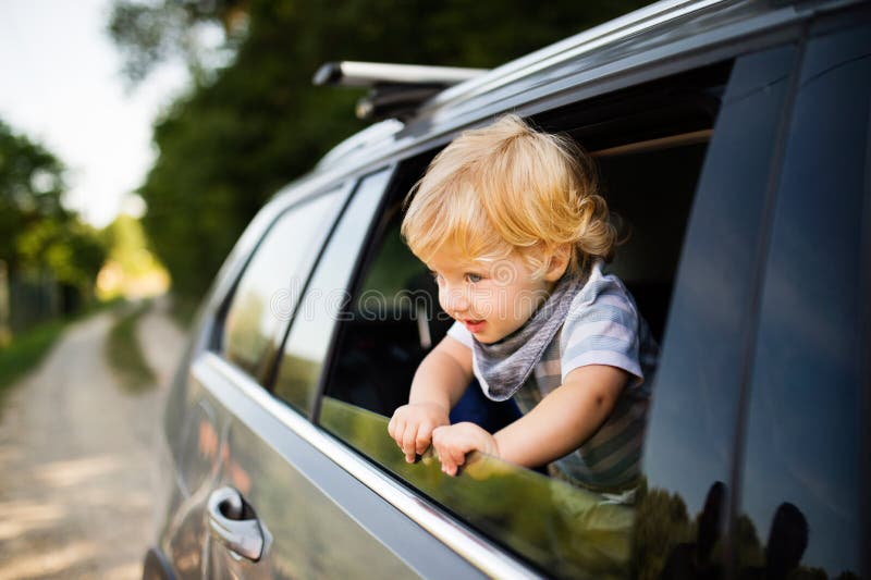 Petit garçon jouant dans la voiture, se penchant hors de la fenêtre photo stock Petit garçon jouant dans la voiture, se penchant hors de la fenêtre photo stock