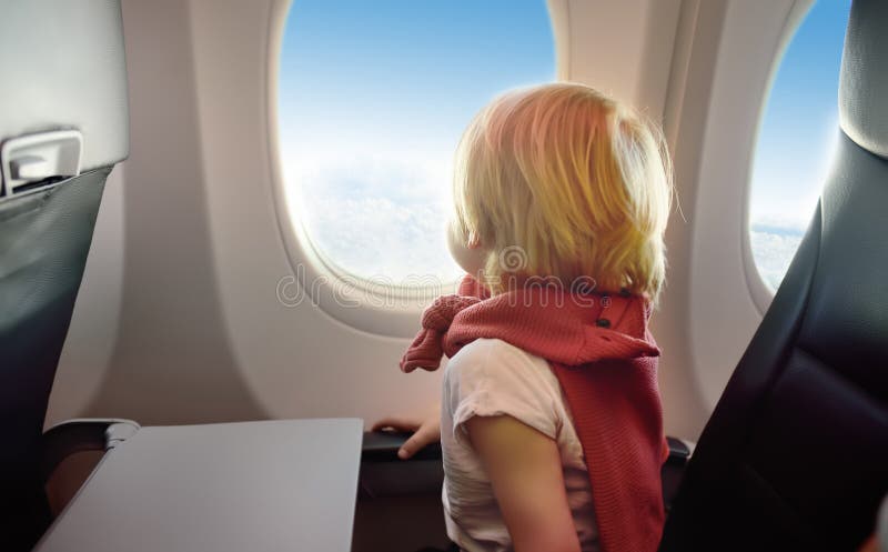 Petit garçon s'asseyant par la fenêtre d'avions pendant le vol photo libre de droits Petit garçon s'asseyant par la fenêtre d'avions pendant le vol photo libre de droits