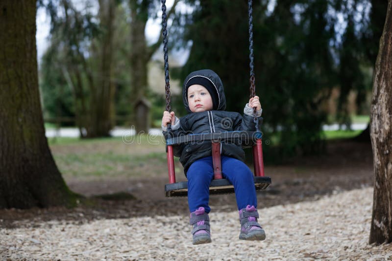 Petit le garçon triste et inquiété balançant seul, seul a laissé sans surveillance, recherchant des parents photos stock Petit le garçon triste et inquiété balançant seul, seul a laissé sans surveillance, recherchant des parents photos stock