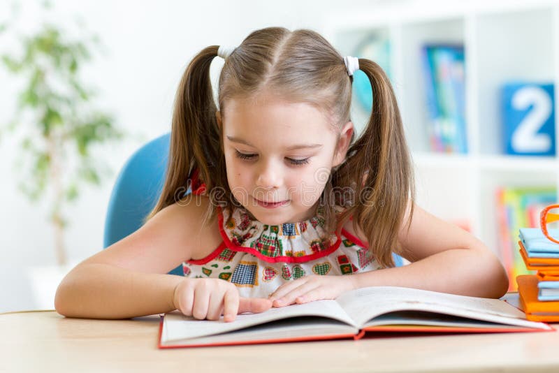 Petit livre de lecture de sourire de fille d'étudiant images stock Petit livre de lecture de sourire de fille d'étudiant images stock