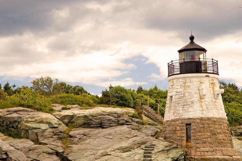 A view of a small lighthouse built on the rocky New England shoreline with steps carved directly in the granite rocks. This lighthouse is in Newport, Rhode Island. A view of a small lighthouse built on the rocky New England shoreline with steps carved directly in the granite rocks. This lighthouse is in Newport, Rhode Island.