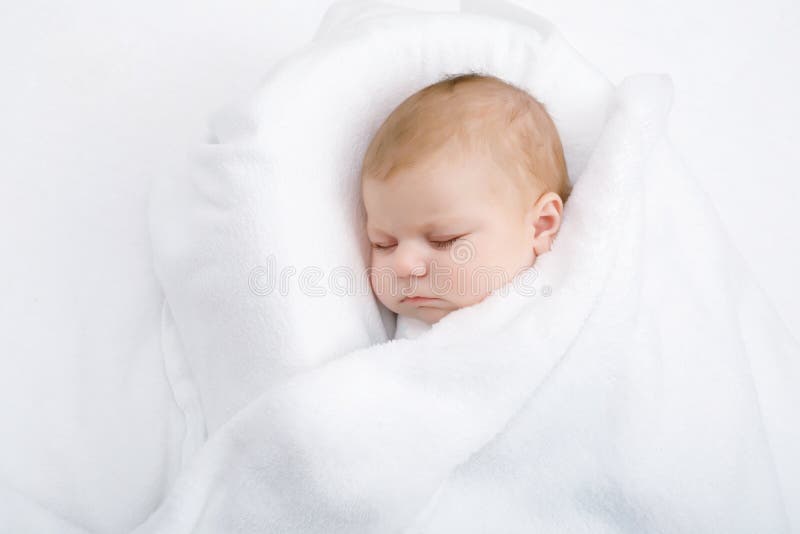 Cute adorable newborn baby wrapped in white blanket, sleeping in kids bed or cocoon. Closeup of peaceful child, little baby girl sleeping. Swaddling as method for calm down child. Cute adorable newborn baby wrapped in white blanket, sleeping in kids bed or cocoon. Closeup of peaceful child, little baby girl sleeping. Swaddling as method for calm down child