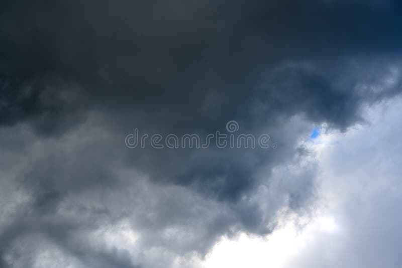 Petit trou bleu minuscule entre les cumulonimbus foncés apportant la pluie photos stock Petit trou bleu minuscule entre les cumulonimbus foncés apportant la pluie photos stock
