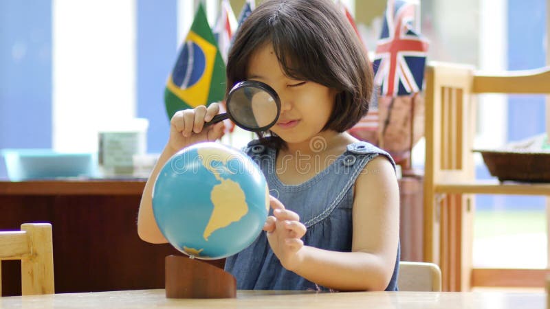 Petit étudiant asiatique regardant le globe