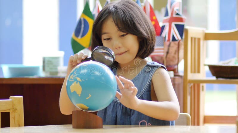 Petit étudiant asiatique regardant le globe