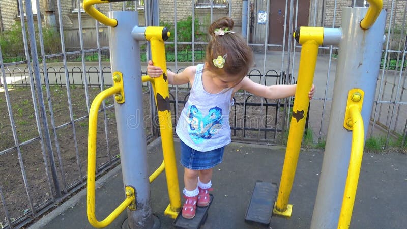 Petite fille adorable balançant sur une oscillation à un terrain de jeu de sport banque de vidéos