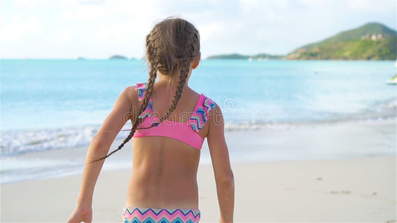 Petite fille adorable courant à la plage tropicale pendant des vacances dans le mouvement lent clips vidéos