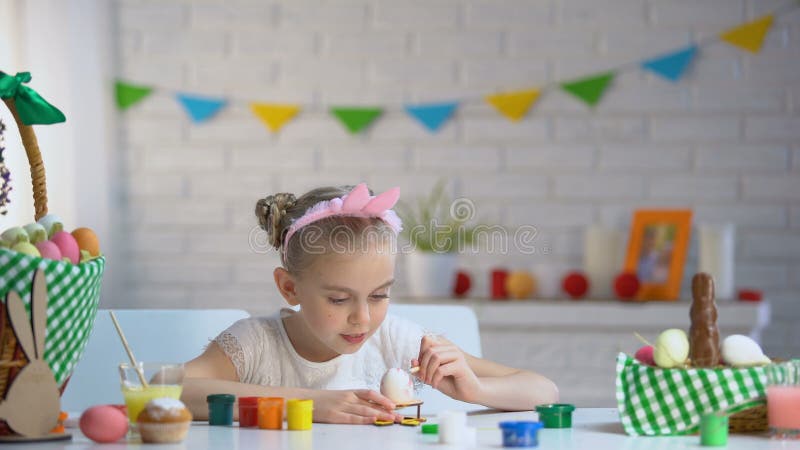 Petite fille adorable décorant des oeufs de pâques avec la peinture colorée, enfant doué banque de vidéos