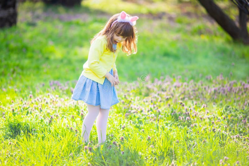 Petite fille adorable s'asseyant ? l'herbe verte jouant dans le jardin sur la chasse ? oeuf de p?ques photos stock Petite fille adorable s'asseyant ? l'herbe verte jouant dans le jardin sur la chasse ? oeuf de p?ques photos stock