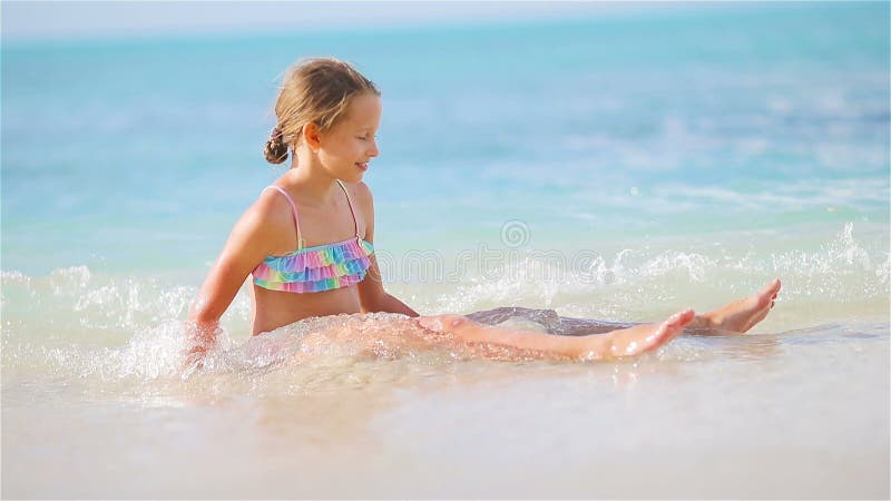 Petite fille adorable s'asseyant sur le sable blanc de neige banque de vidéos