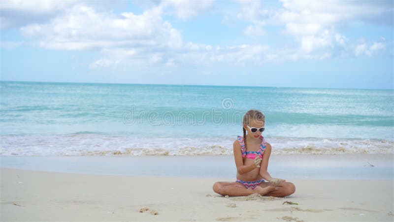 Petite fille adorable se trouvant sur la plage sablonneuse blanche banque de vidéos