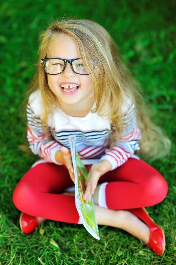 Petite fille adorable tenant le livre et rire photos stock Petite fille adorable tenant le livre et rire photos stock