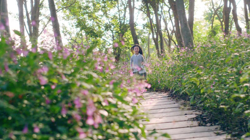 Petite fille asiatique courant en bois en parc