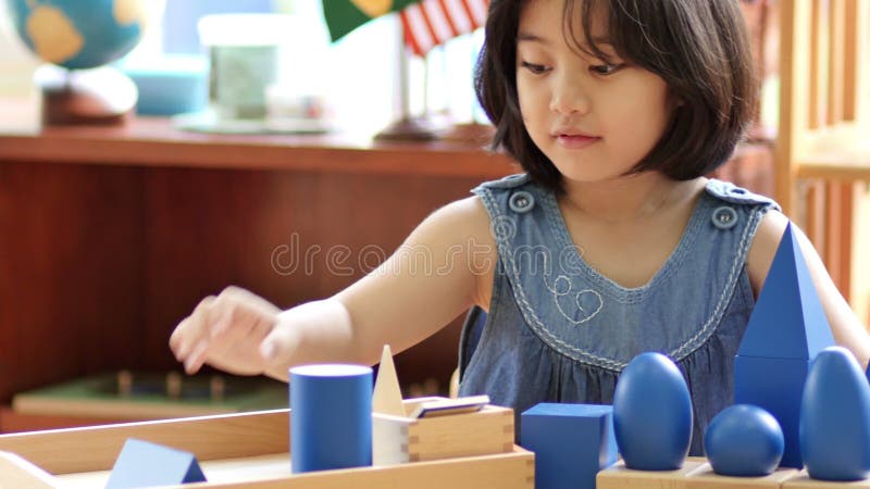 Petite fille asiatique empilant des blocs de montessori