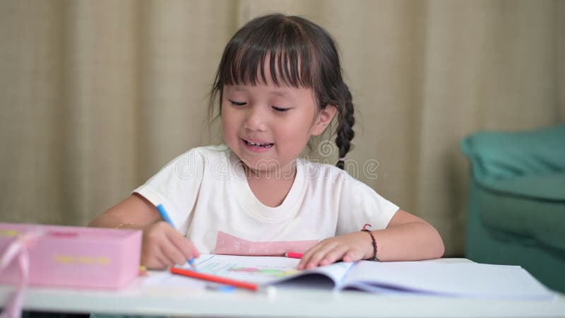 Petite fille asiatique faisant le dessin d'ouverture de la maison d'école et la peinture à la maison banque de vidéos