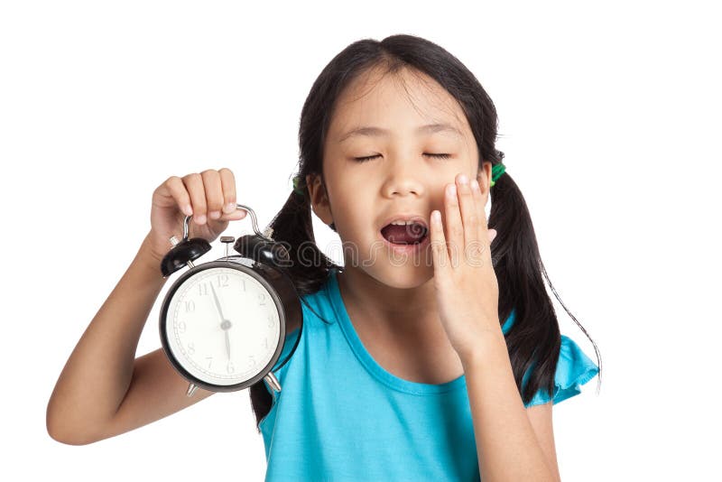 Petite fille asiatique somnolente avec une horloge image libre de droits Petite fille asiatique somnolente avec une horloge image libre de droits