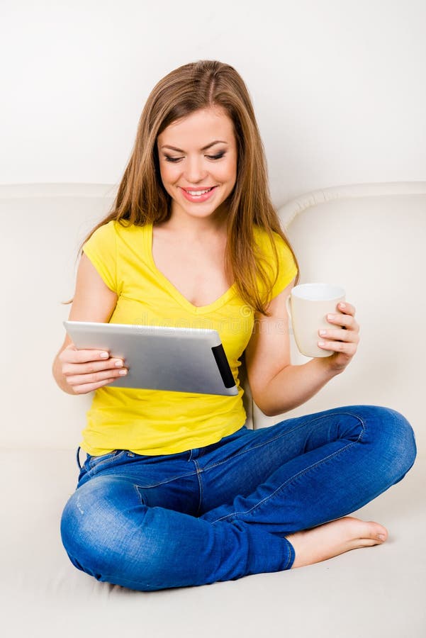 Petite fille assise avec des jambes croisées et lisant des nouvelles dans son tablette PC images libres de droits