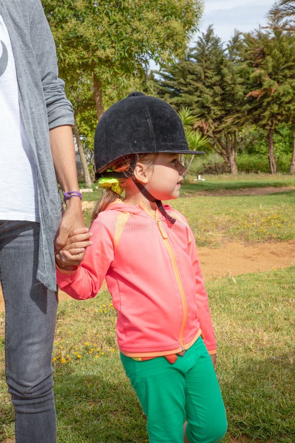 Petite fille avec chapeau tenant la main de la mère attendant de monter à cheval