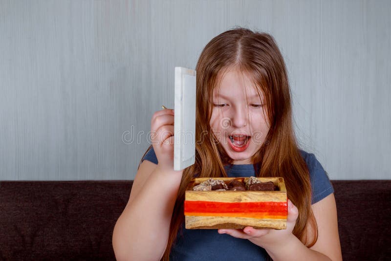 Petite fille avec des sucreries dans la boîte étonnée tenant une canne de sucrerie Noël heureux photo stock Petite fille avec des sucreries dans la boîte étonnée tenant une canne de sucrerie Noël heureux photo stock