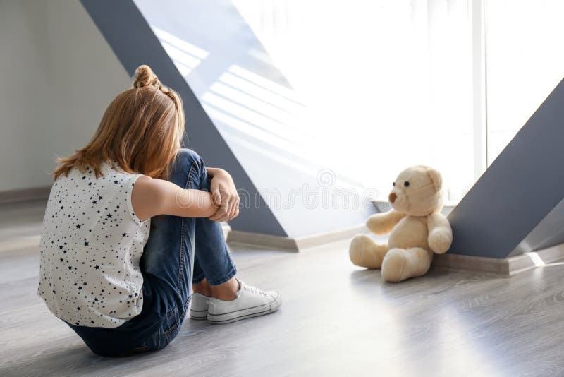 Petite fille avec l'ours de nounours se reposant sur le plancher près de la fenêtre photographie stock libre de droits Petite fille avec l'ours de nounours se reposant sur le plancher près de la fenêtre photographie stock libre de droits