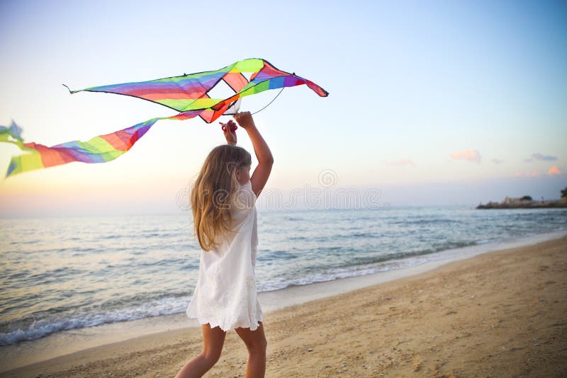 Petite fille avec le cerf-volant de vol sur la plage tropicale au coucher du soleil image stock Petite fille avec le cerf-volant de vol sur la plage tropicale au coucher du soleil image stock