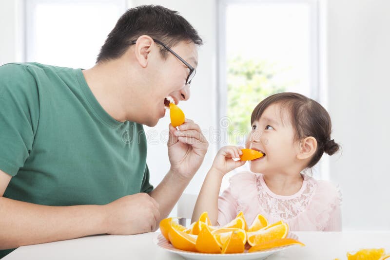 Petite fille avec le père mangeant l'orange