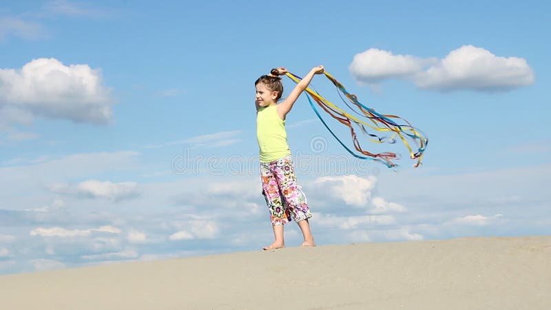 Petite fille avec les rubans colorés sur la plage