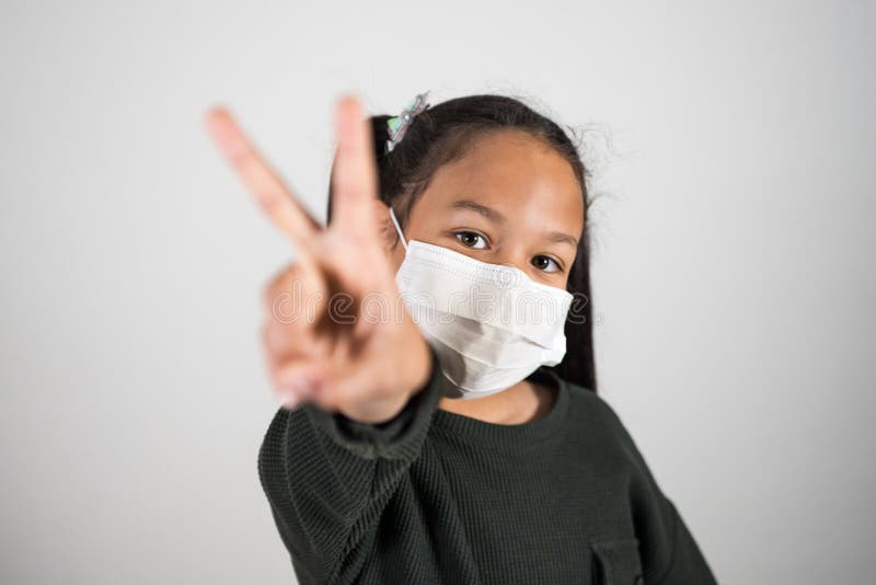 Petite fille avec masque médical montrer v signe avec main soins de santé et contrôle des infections. concept de positivisme contr