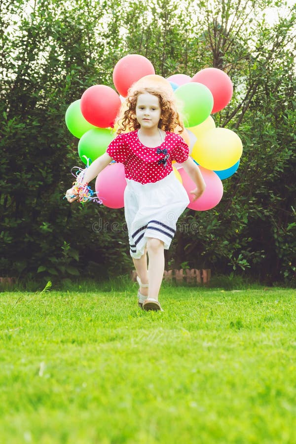 Petite fille bouclée courant avec les ballons colorés Enfance heureux