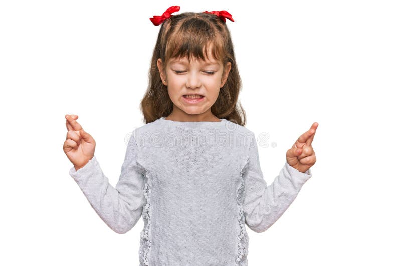 Petite fille caucasienne vêtue de vêtements décontractés gestant doigt croisé souriant avec espoir et yeux fermés images stock