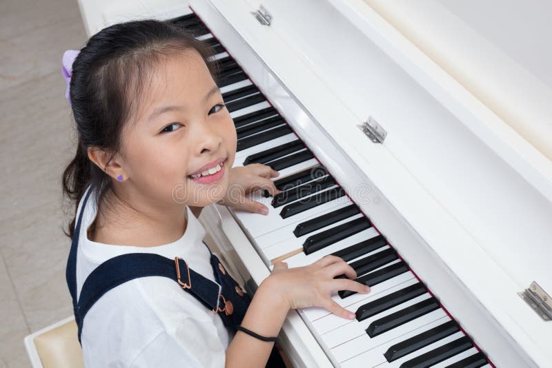 Petite fille chinoise asiatique heureuse jouant le piano classique à la maison images libres de droits Petite fille chinoise asiatique heureuse jouant le piano classique à la maison images libres de droits