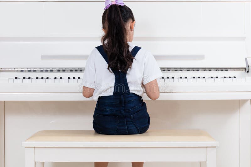 Petite fille chinoise asiatique jouant le piano classique à la maison photographie stock libre de droits Petite fille chinoise asiatique jouant le piano classique à la maison photographie stock libre de droits