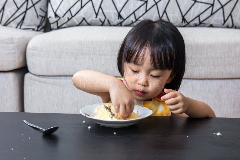 Petite fille chinoise asiatique mangeant du gâteau au fromage d'anniversaire photo stock Petite fille chinoise asiatique mangeant du gâteau au fromage d'anniversaire photo stock
