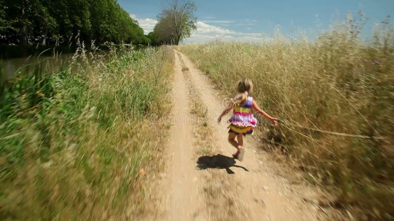 Petite fille courant le long de la voie de chemin en nature