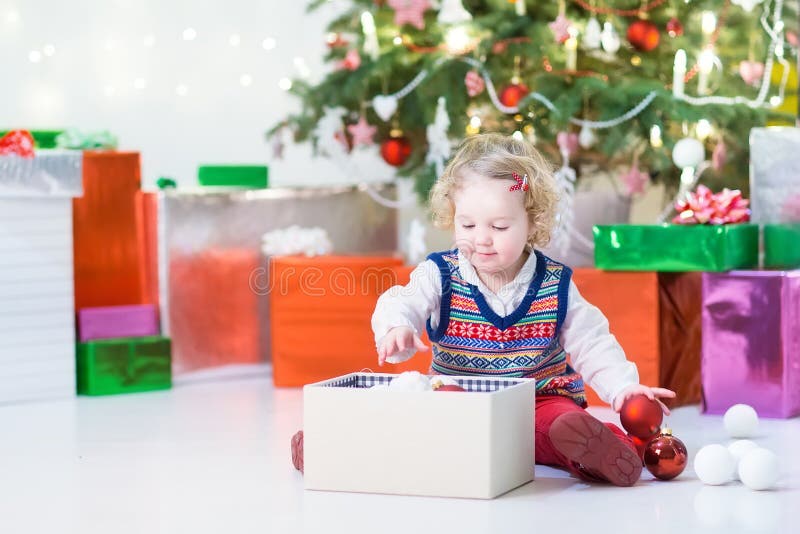 Petite fille d'enfant en bas âge ouvrant son cadeau de Noël sous un bel arbre de Noël photographie stock libre de droits Petite fille d'enfant en bas âge ouvrant son cadeau de Noël sous un bel arbre de Noël photographie stock libre de droits