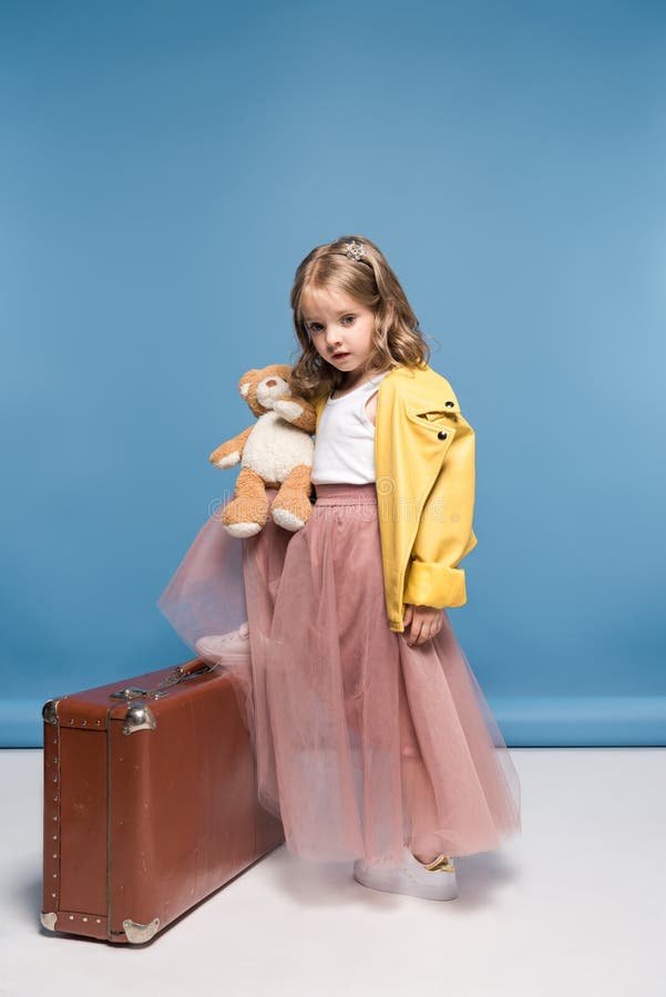 Petite fille dans la jupe rose posant avec l'ours et la valise de nounours photographie stock Petite fille dans la jupe rose posant avec l'ours et la valise de nounours photographie stock
