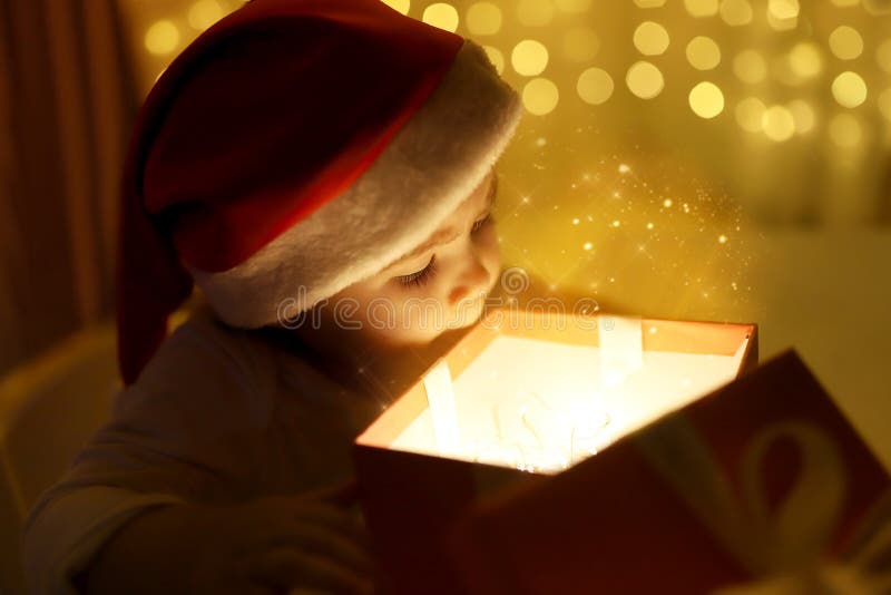 Petite Fille De Noël Dans Un Chapeau Santa Regarde Dans Une Boîte